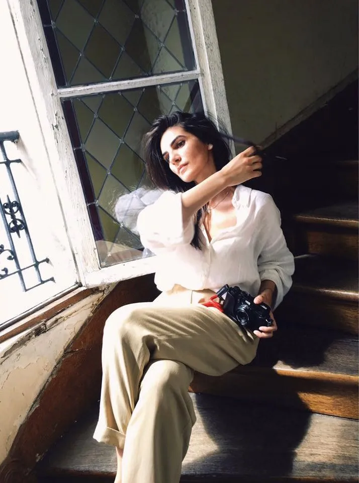 Antonia Oprea sitting on a window ledge, camera in hand