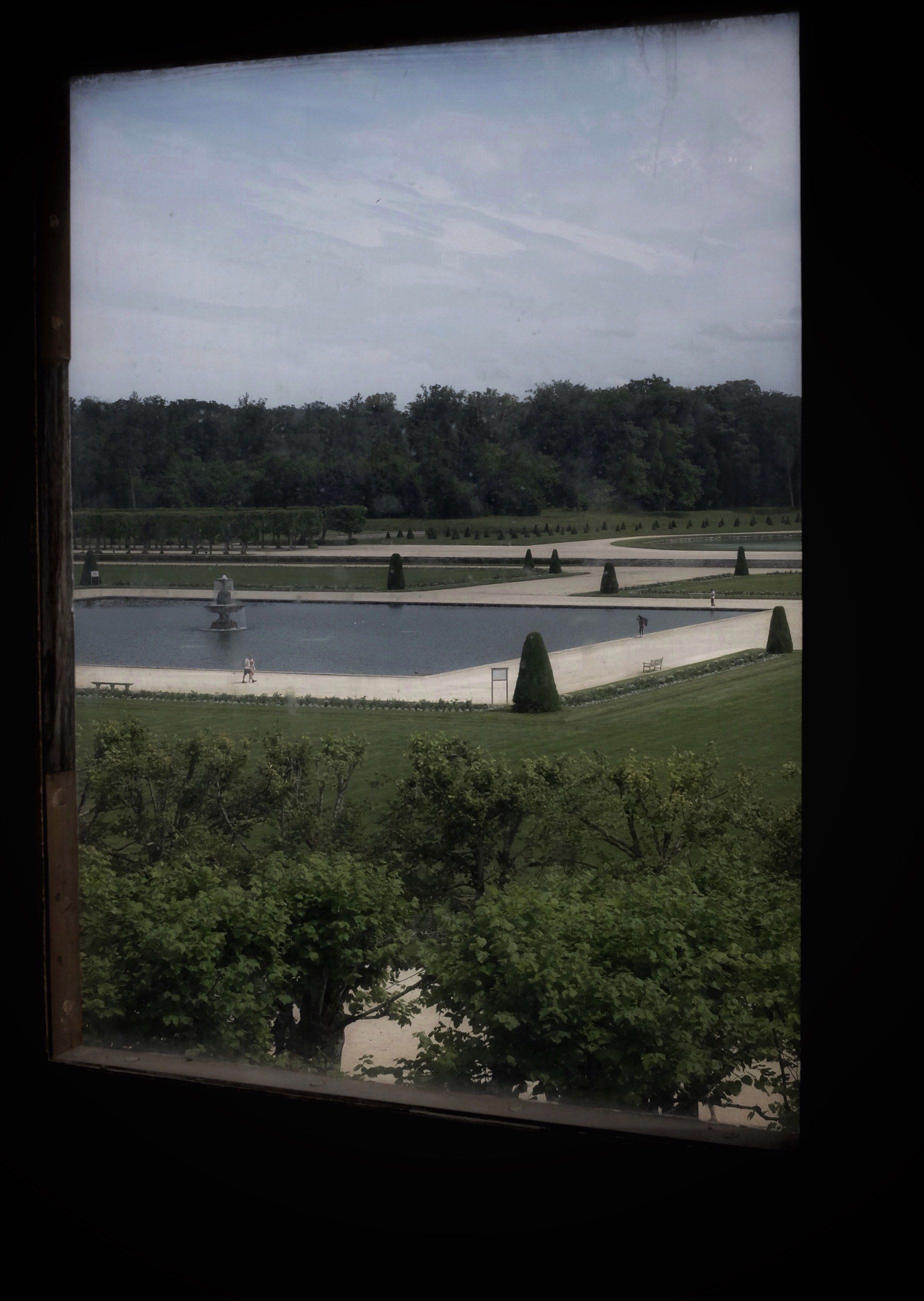 A formal garden and pond seen through a window