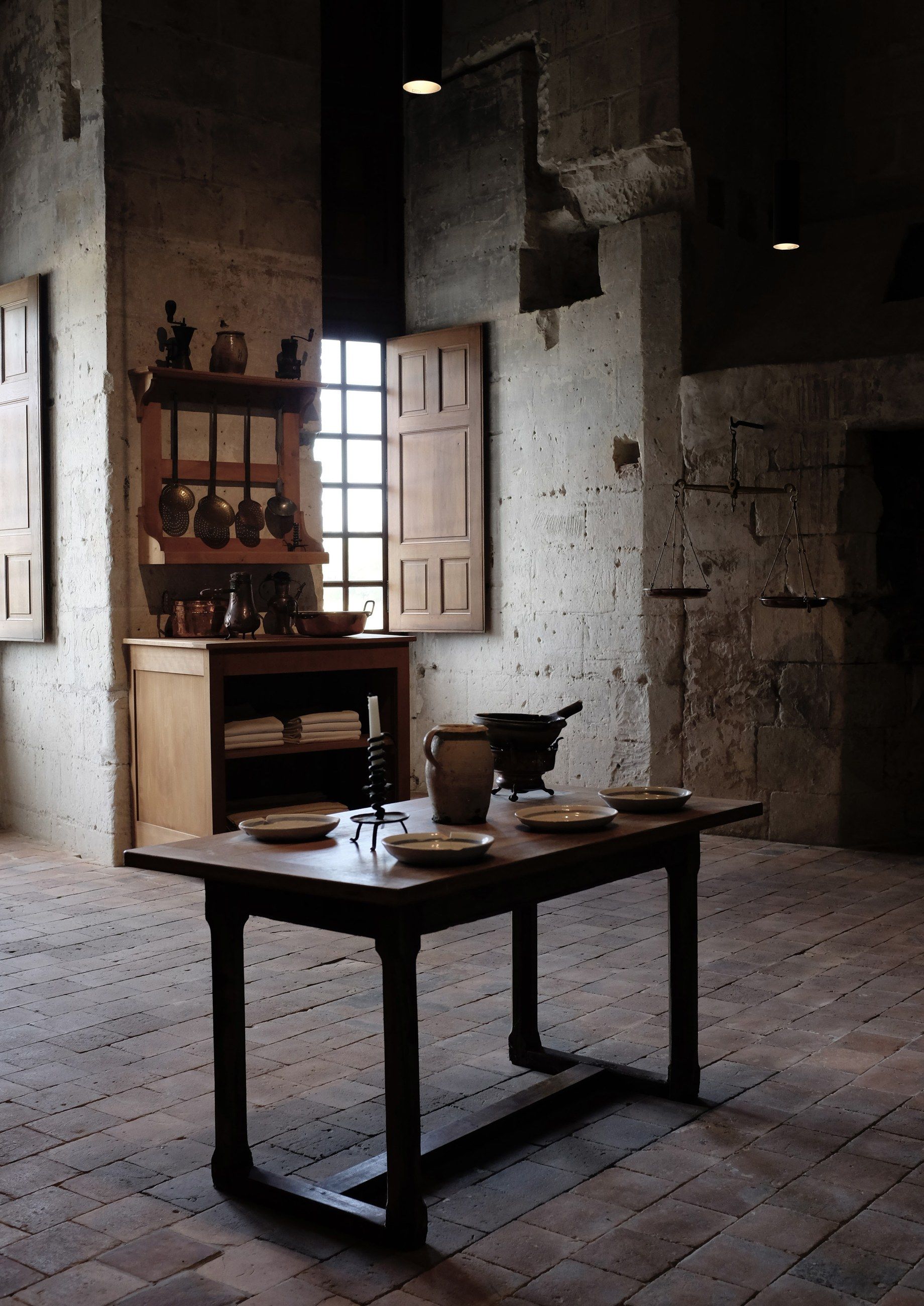 A stone kitchen with a wooden table and a small window