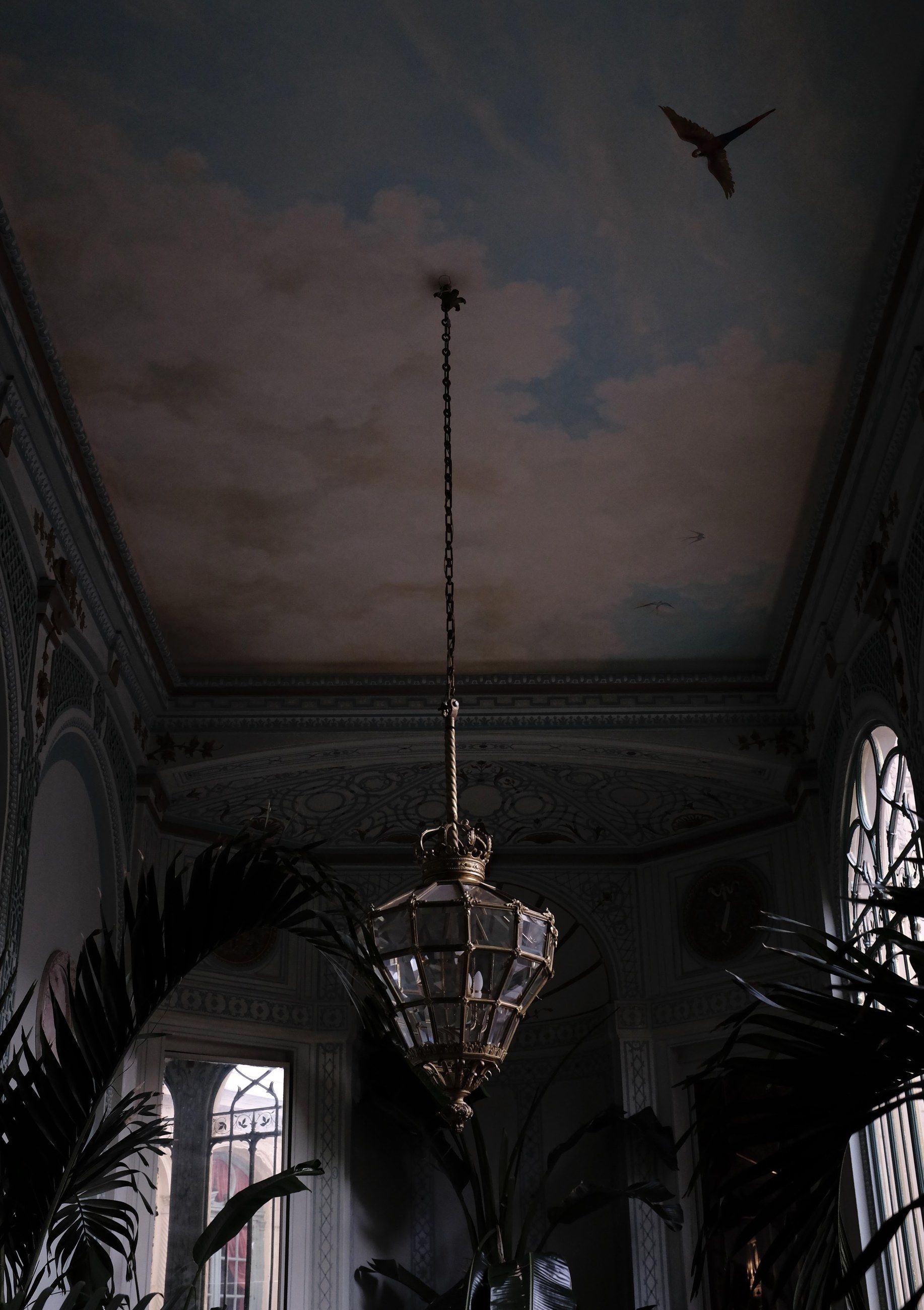 A painted ceiling with a chandelier and a bird in flight